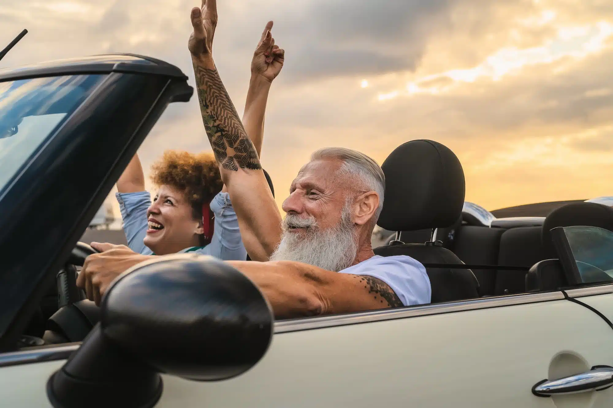 A senior couple driving a convertible and having fun