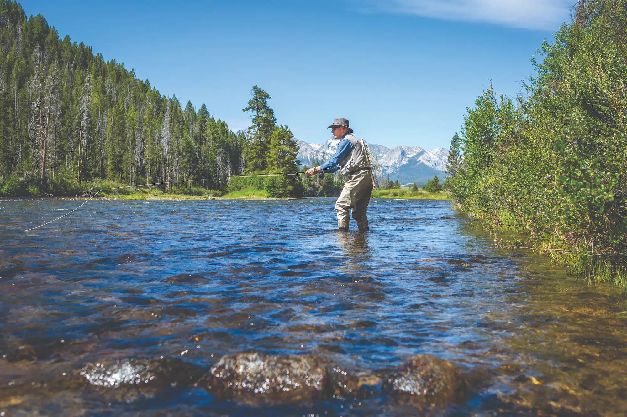 Older man fly fishing in a river