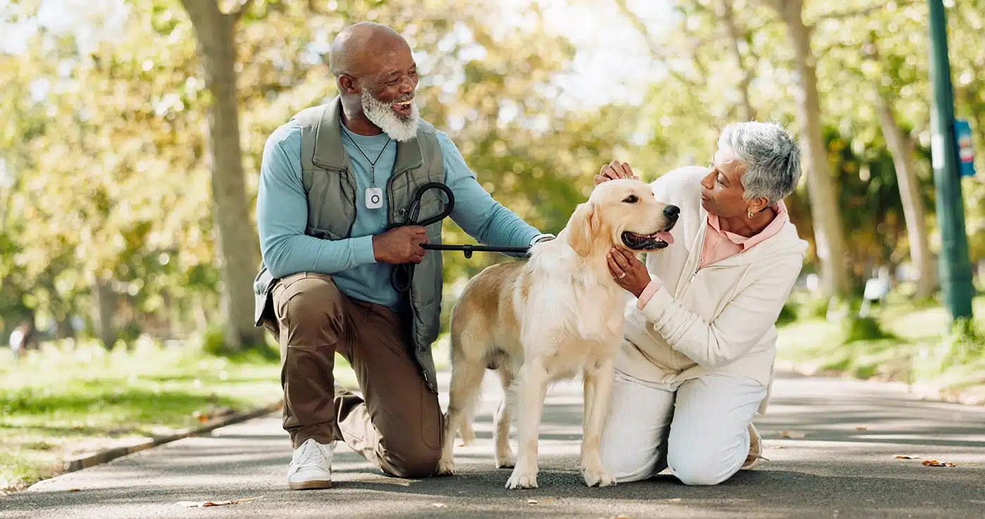 Two seniors petting a dog