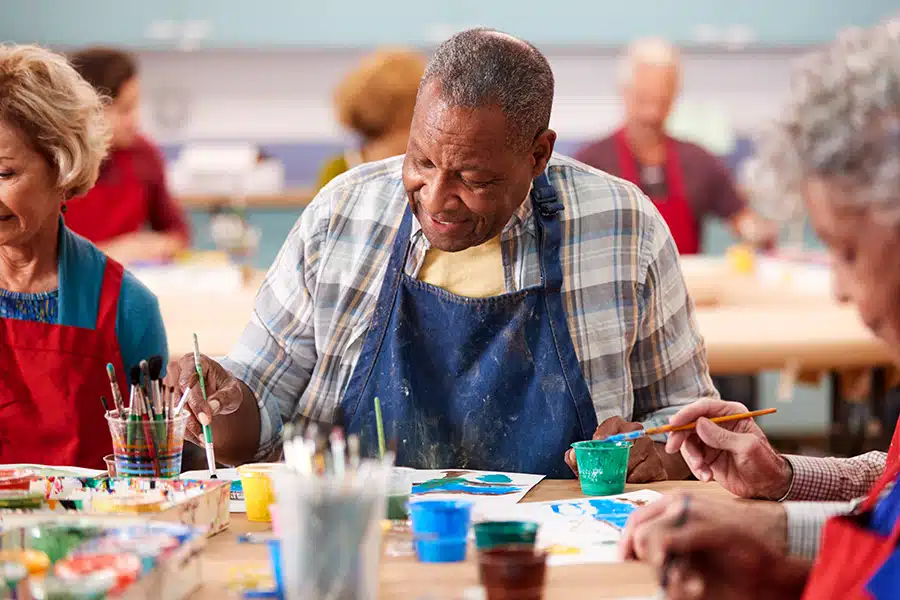 Senior man painting with brush during art class at community centre