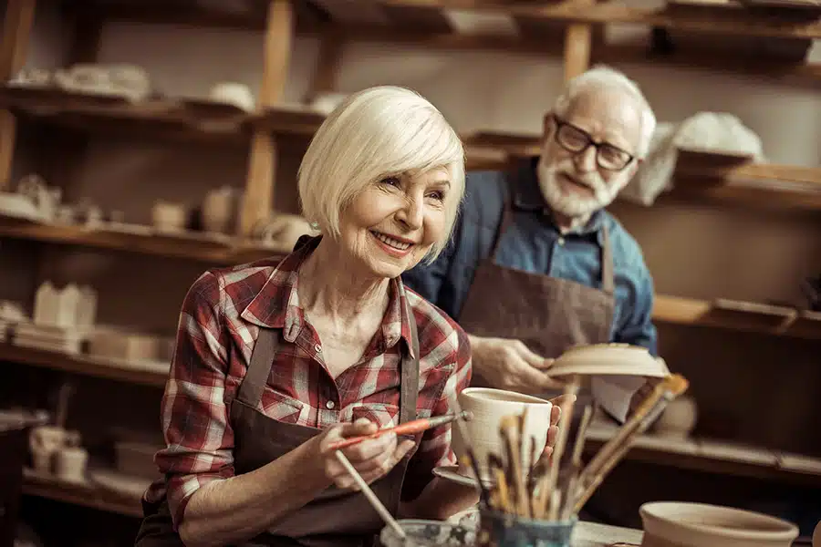 Senior woman painting clay pot during pottery workshop