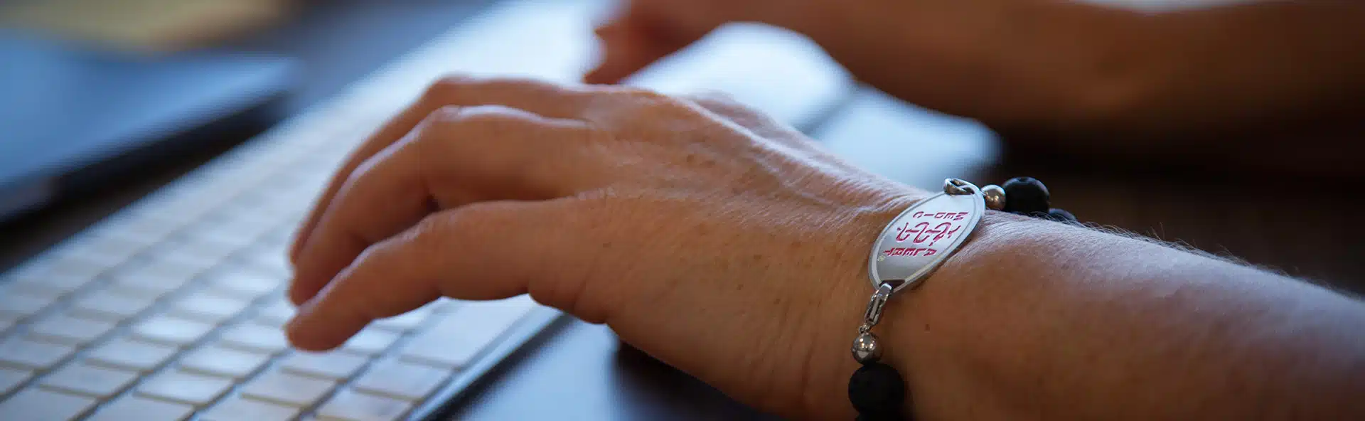 Person typing on a keyboard while wearing a MedicAlert Medical ID