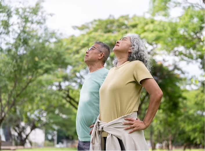 Two seniors stretching outside at the park