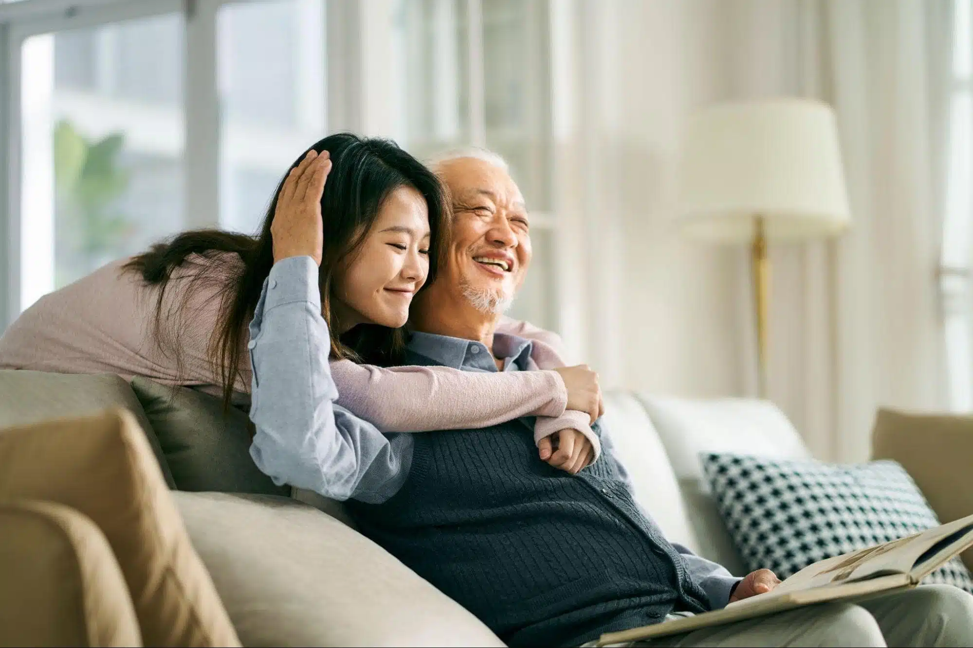 Daughter hugging father while he is sitting on the couch