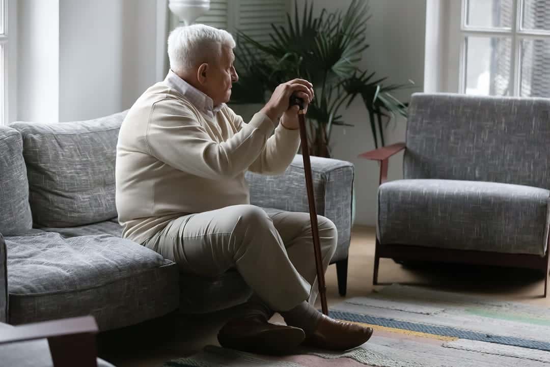 Une personne âgée assise, regardant par la fenêtre