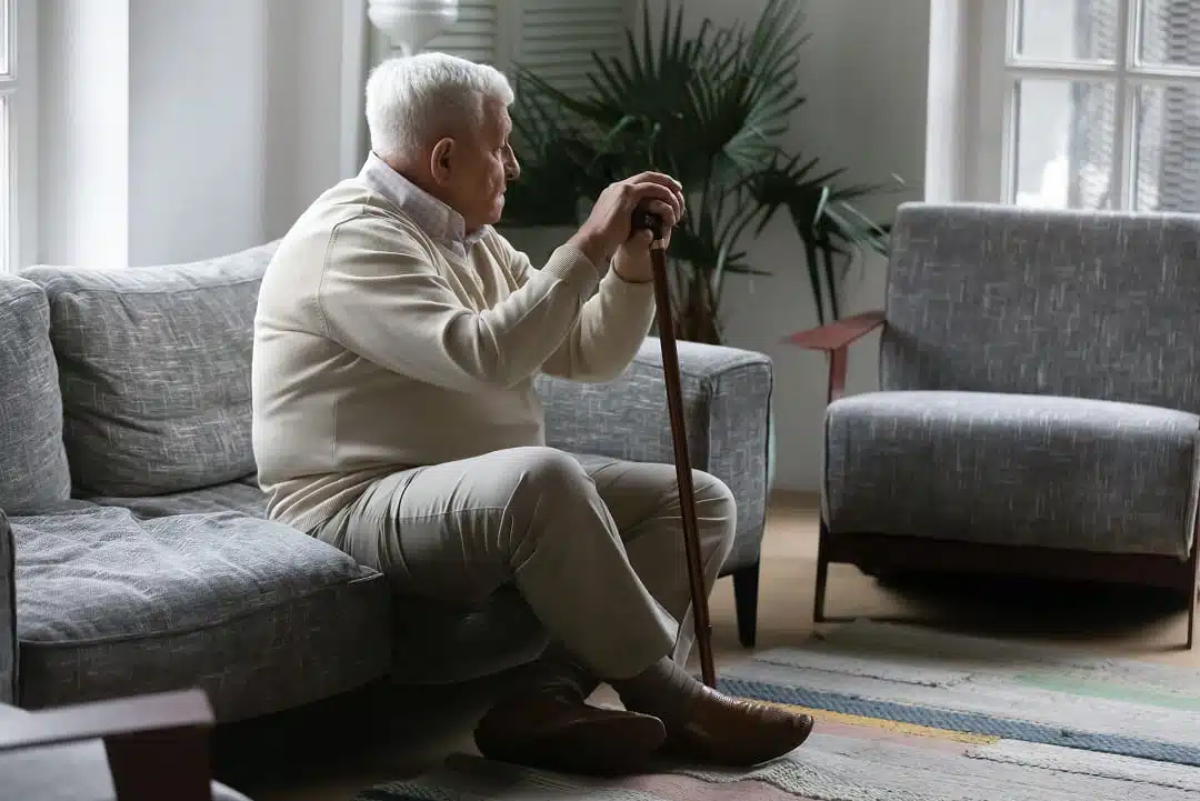A senior sitting down staring outside a window