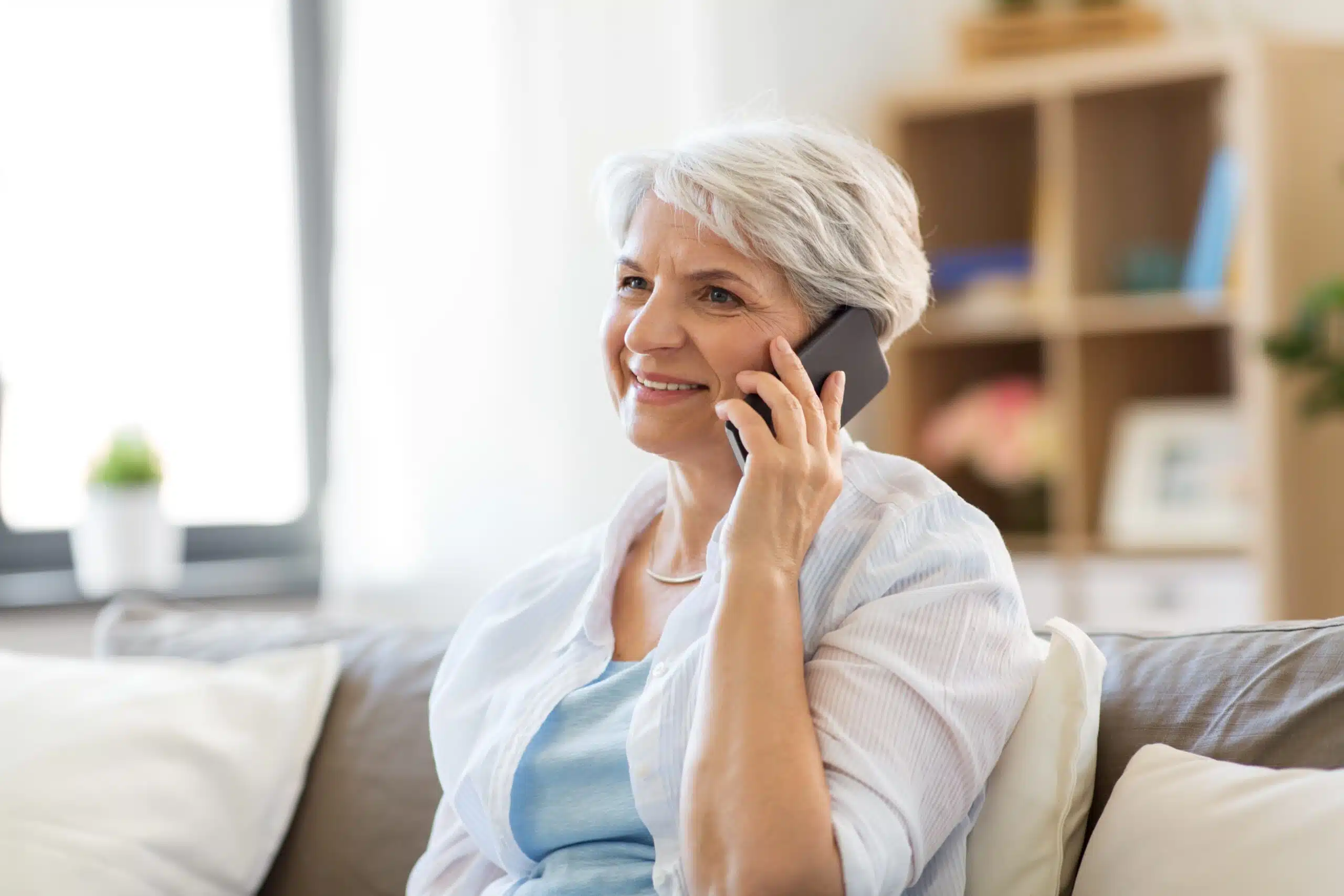 A senior smiling while on the phone.