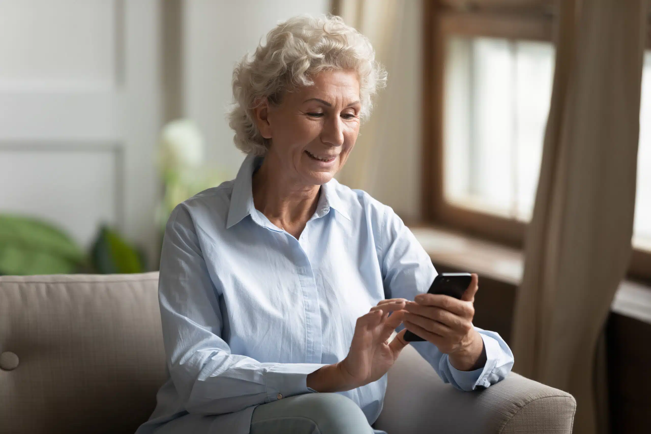 Older woman looking at her smart home technology on her phone.