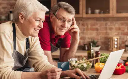 Older couple in the kitchen looking at their laptop inquisitively