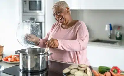Older woman in the kitchen cooking and smiling