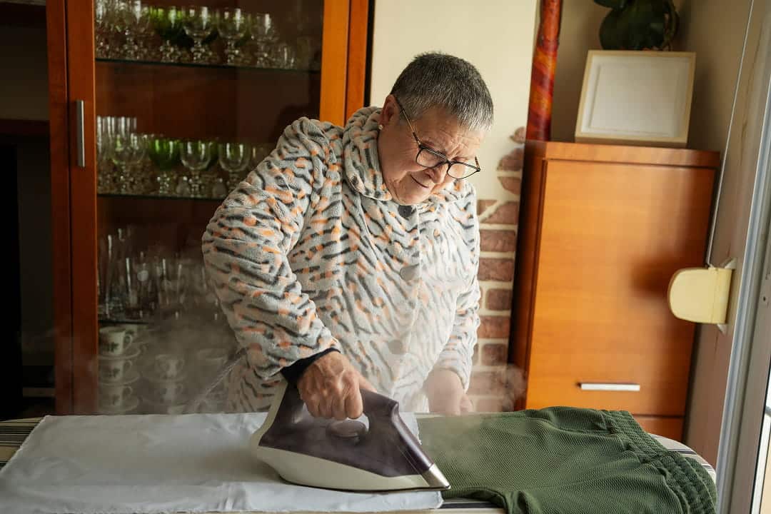 Une personne âgée repassant son pantalon