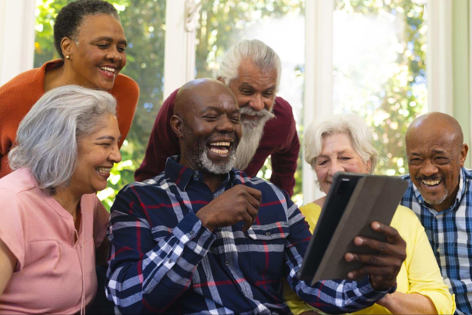 Seniors laughing while looking at a tablet