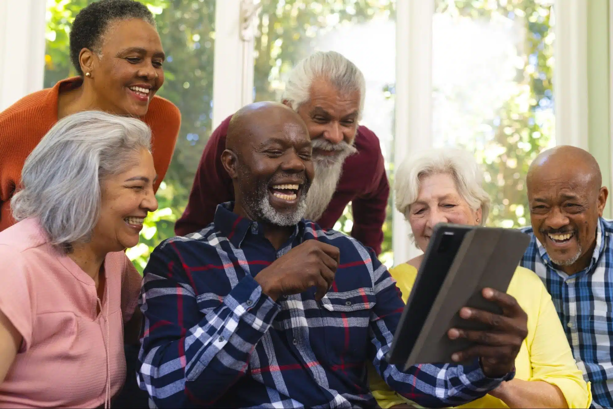 Seniors laughing while looking at a tablet
