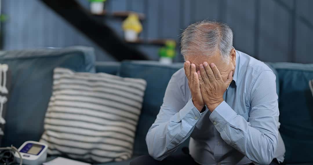 A senior being stressed covering their face