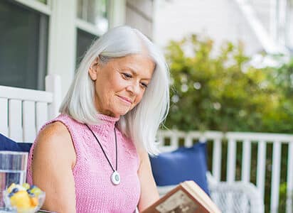 Woman reading a book sitting on a chair outside